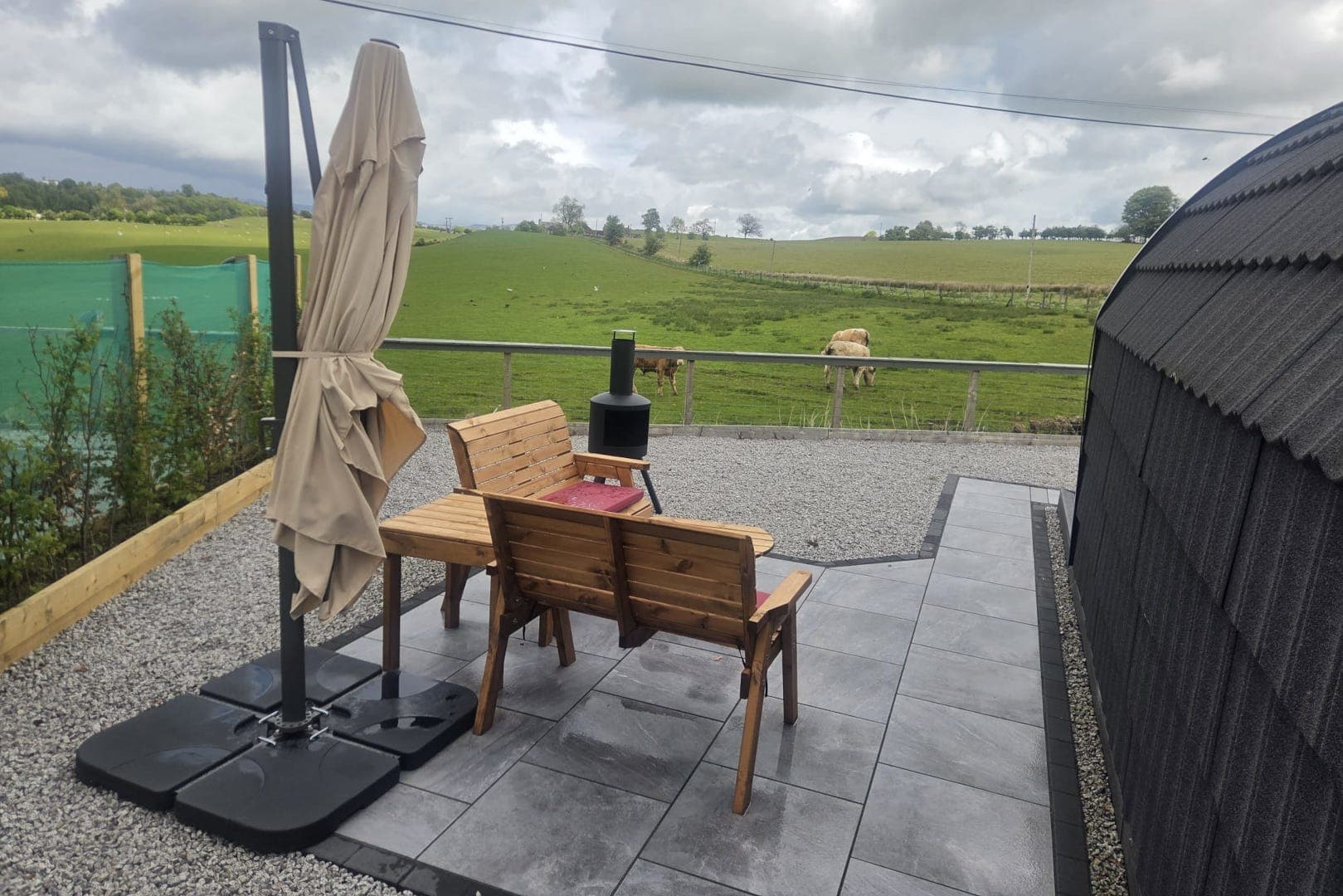 The patio with a chiminea and farmland views, a pod in the background