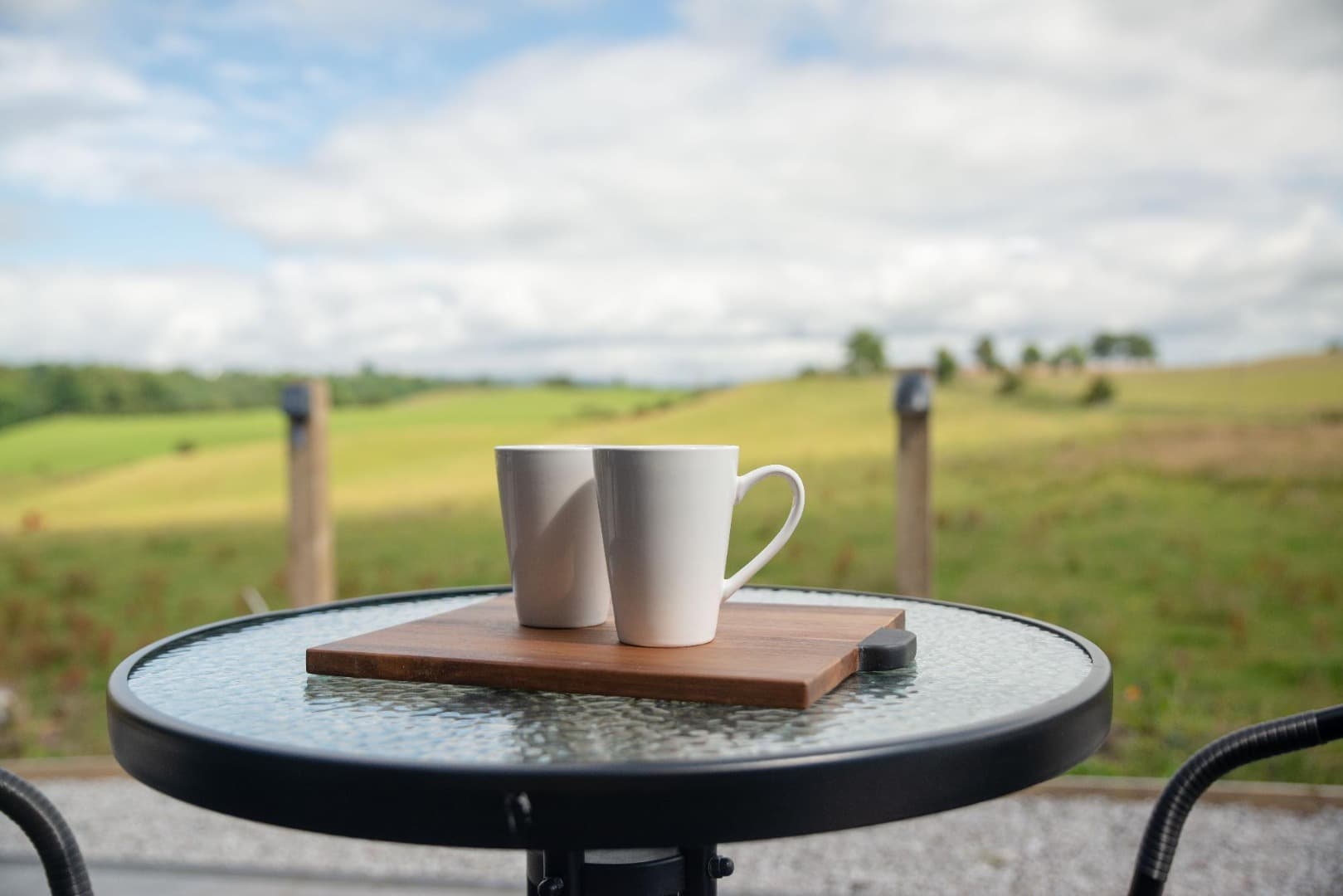 Coffee on the decking table, looking out over open fields