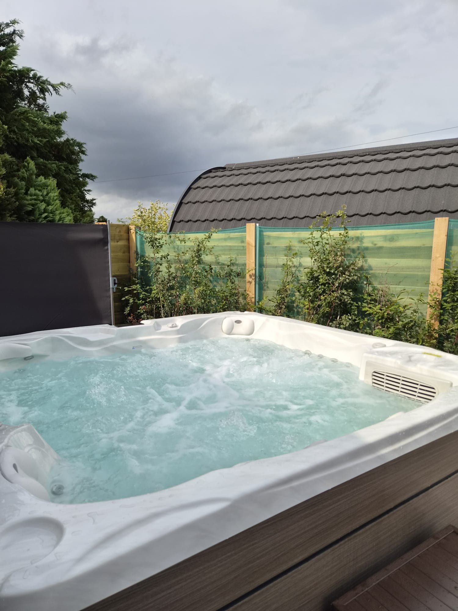 The Thistle Pod hot tub screened by young hedging and timber fencing