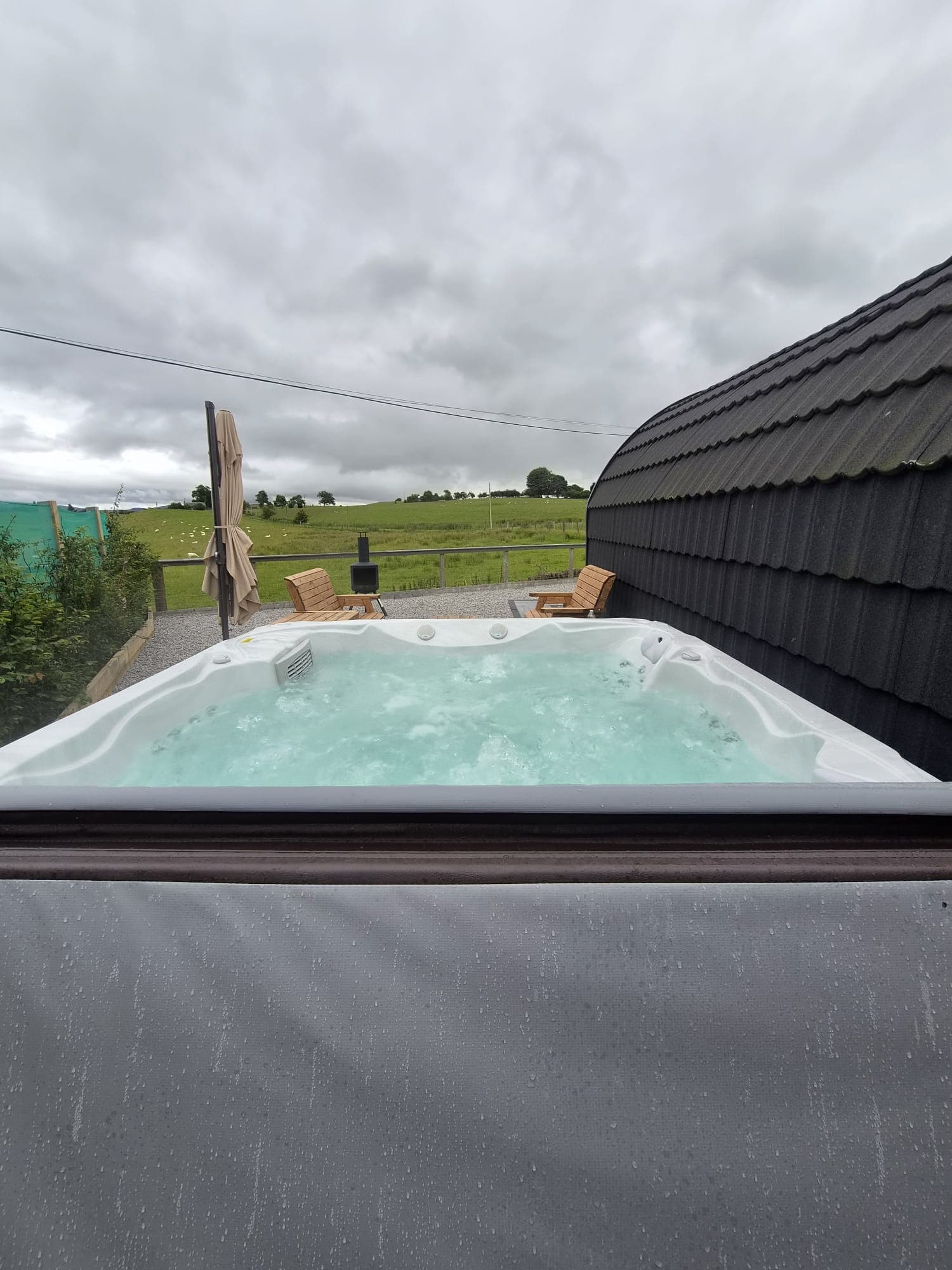The Thistle Pod hot tub with wooden loungers and a chiminea alongside