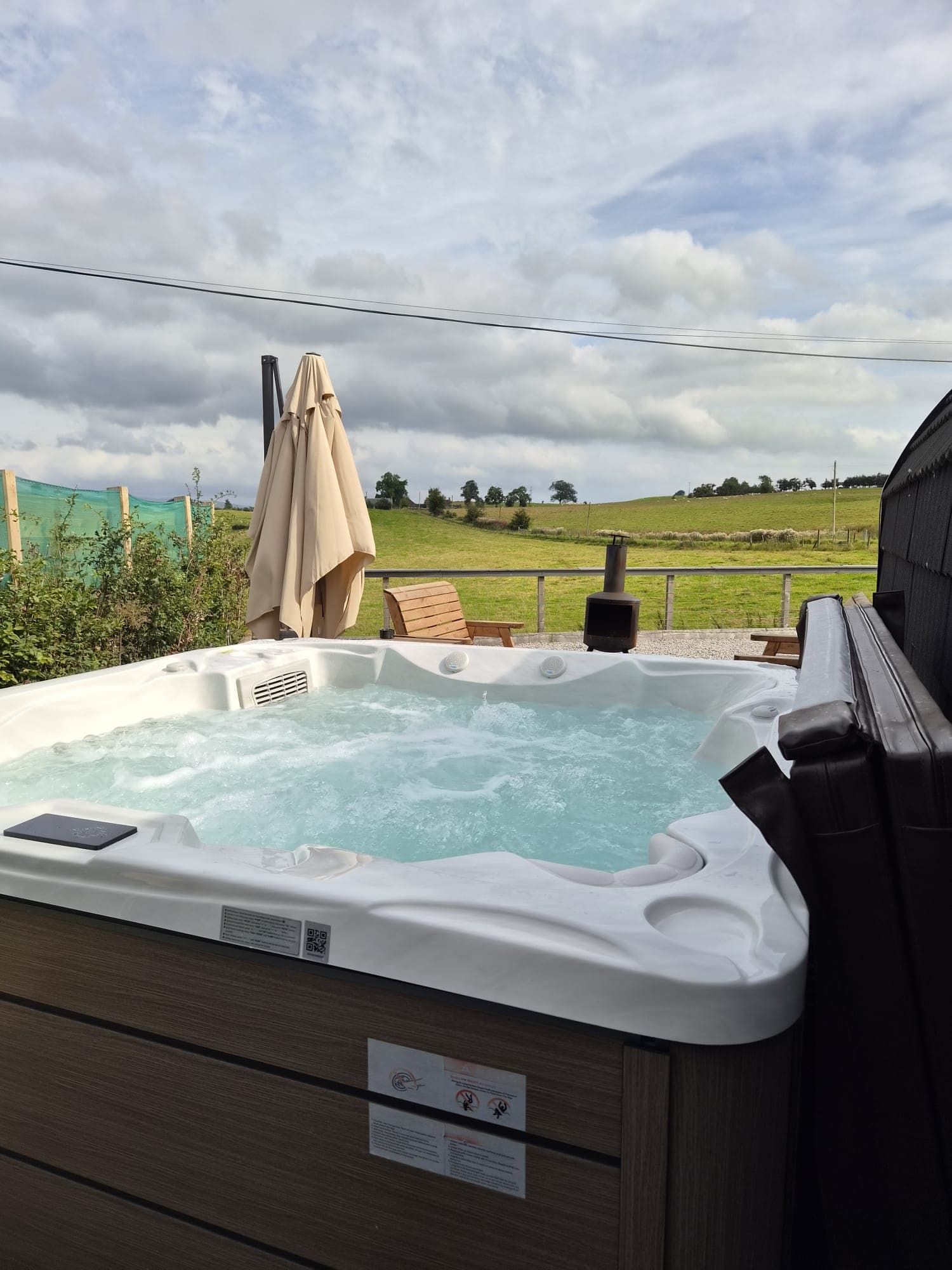 The Rose Pod's hot tub with the umbrella and chiminea on the patio