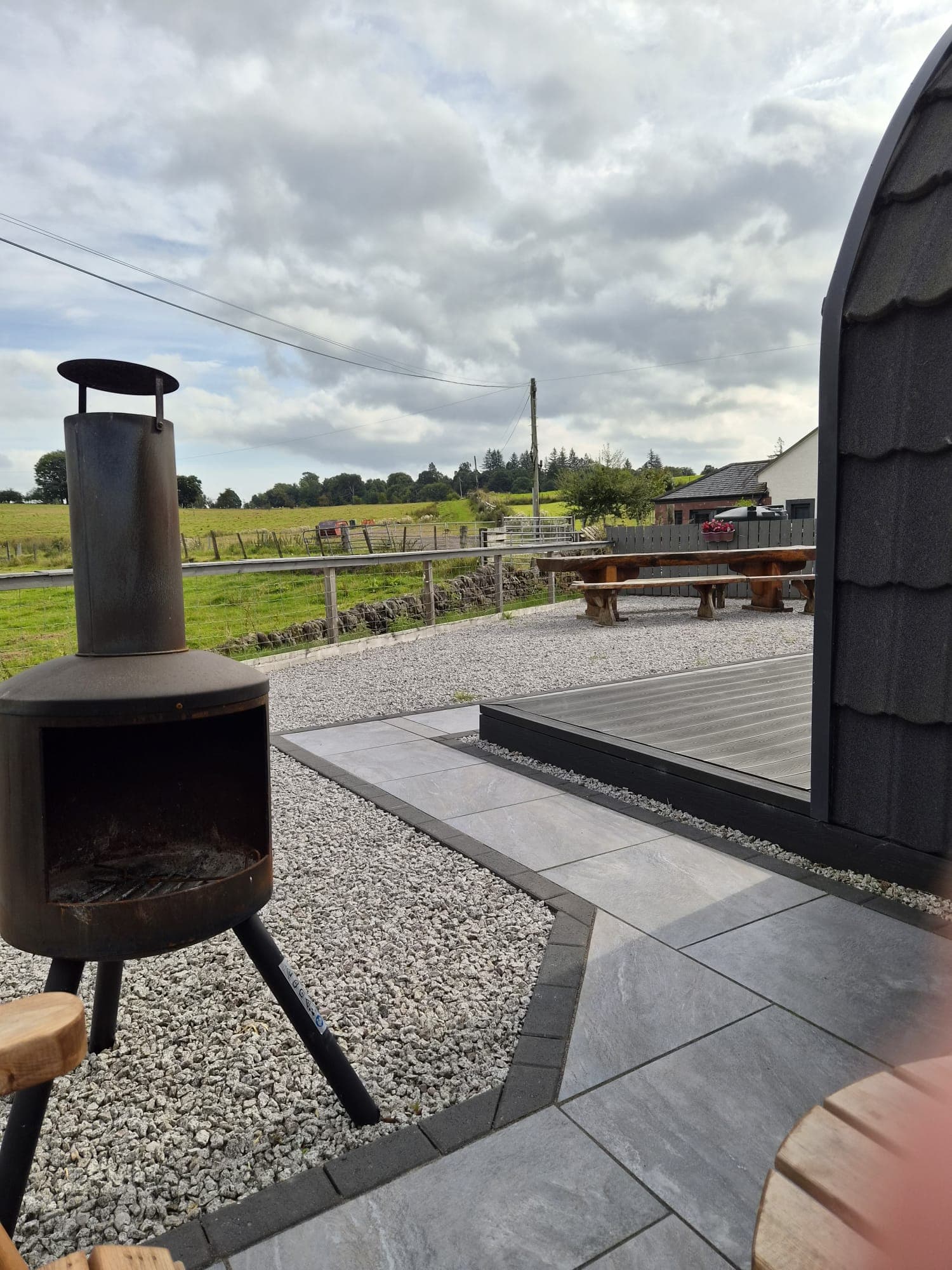 The Rose Pod's patio with a chiminea, live-edge bench and farmland view
