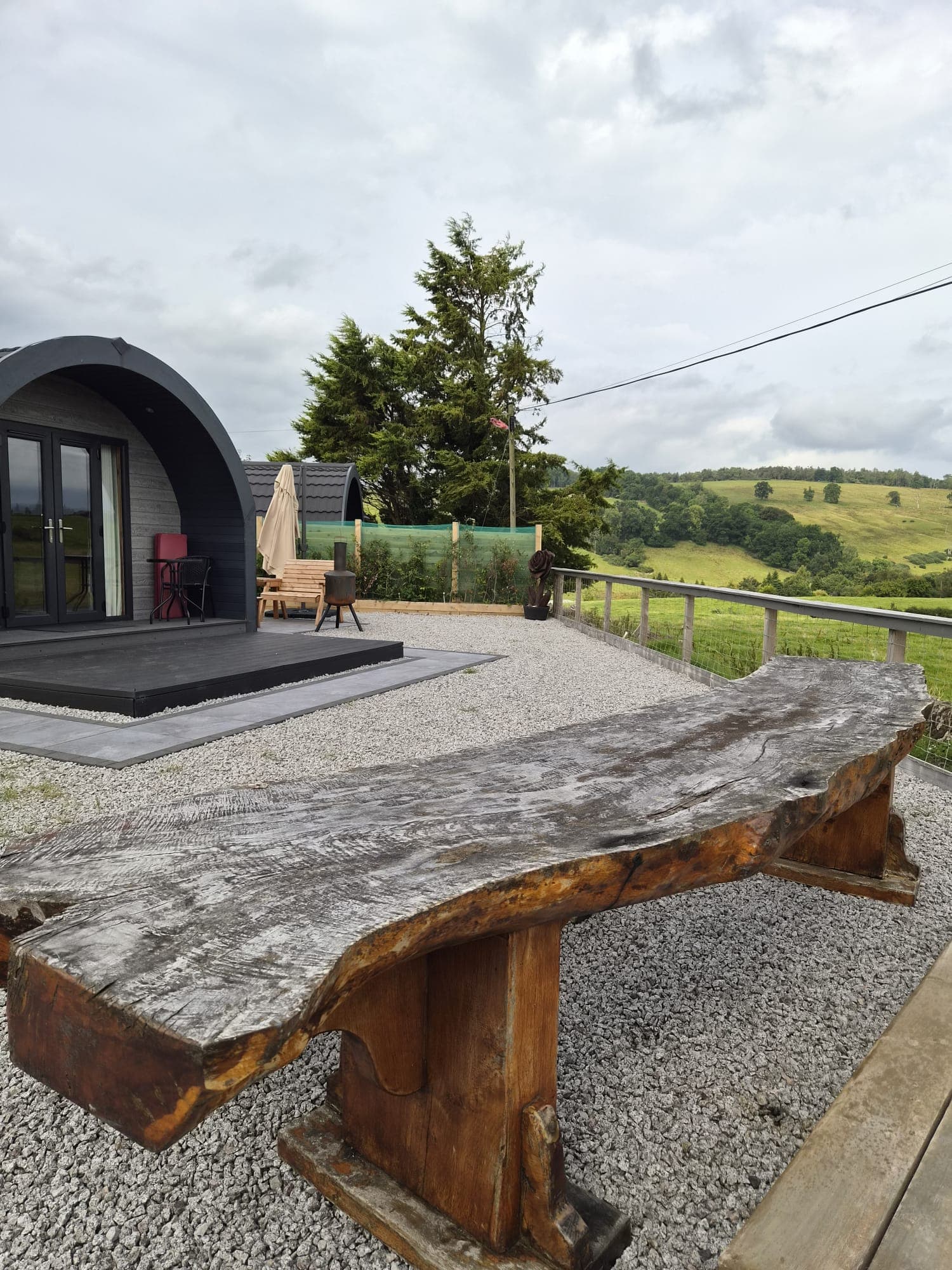 The Thistle Pod's deck with a live-edge oak bench, looking out over the farm