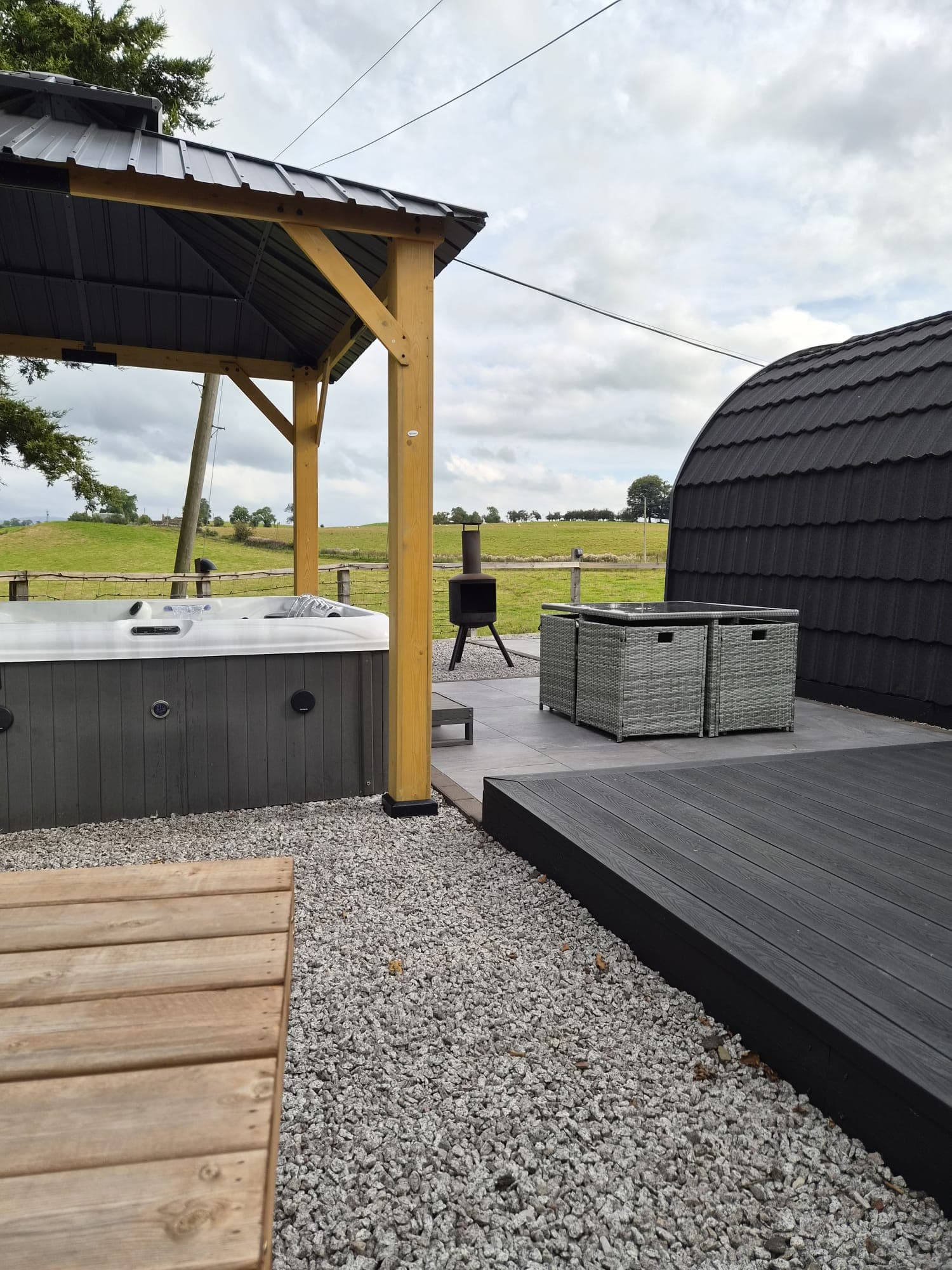 The Thistle Pod hot tub under its gazebo, with rattan seating alongside